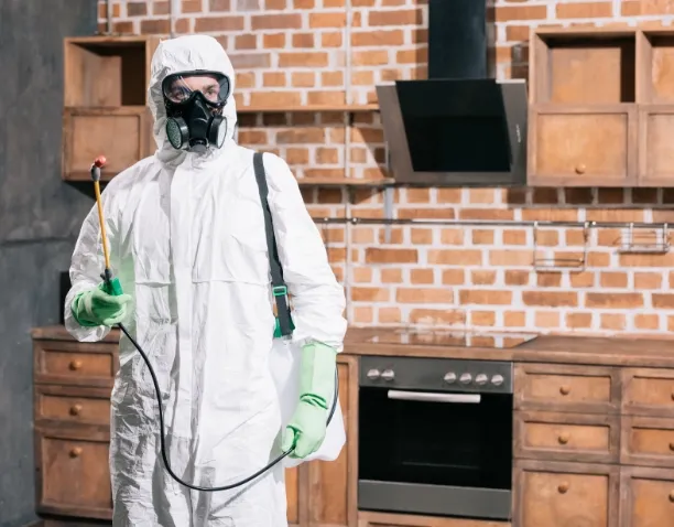 /pest-control-worker-standing-with-sprayer-in-kitchen