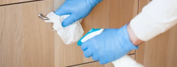 man hands in gloves disinfecting chest of drawers handle, killing virus on surface